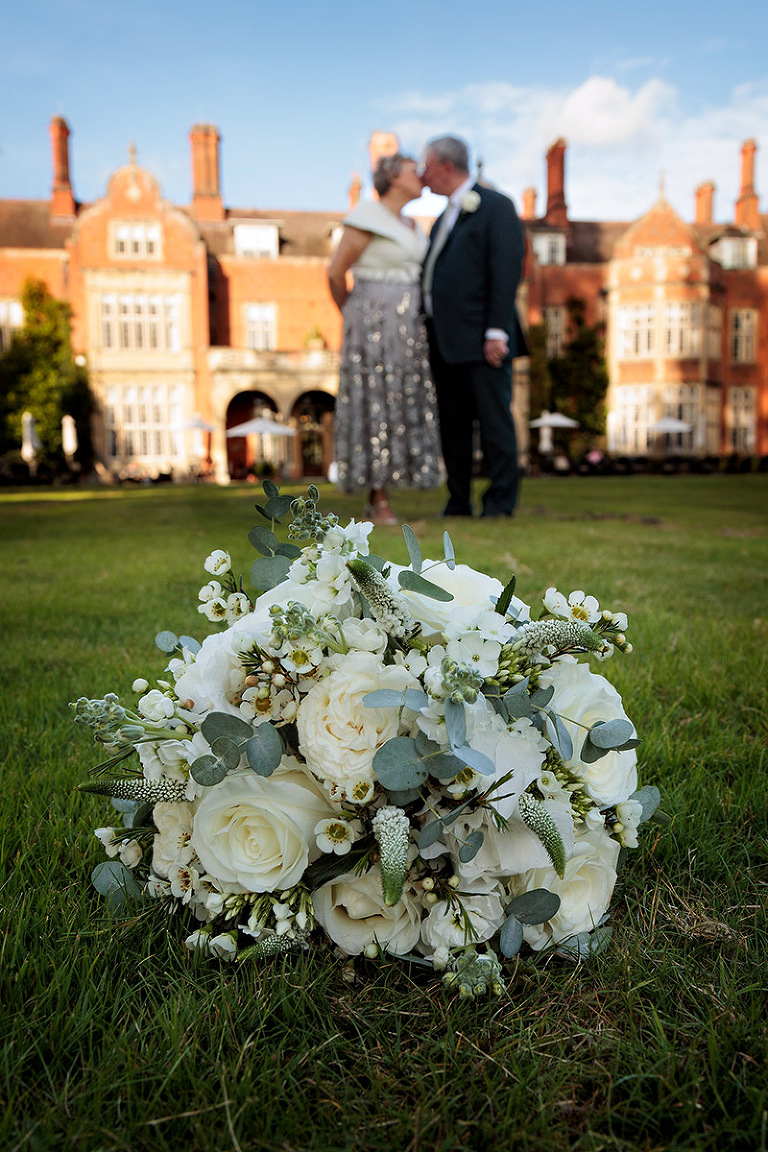 wedding bouquet with couple kissing in background